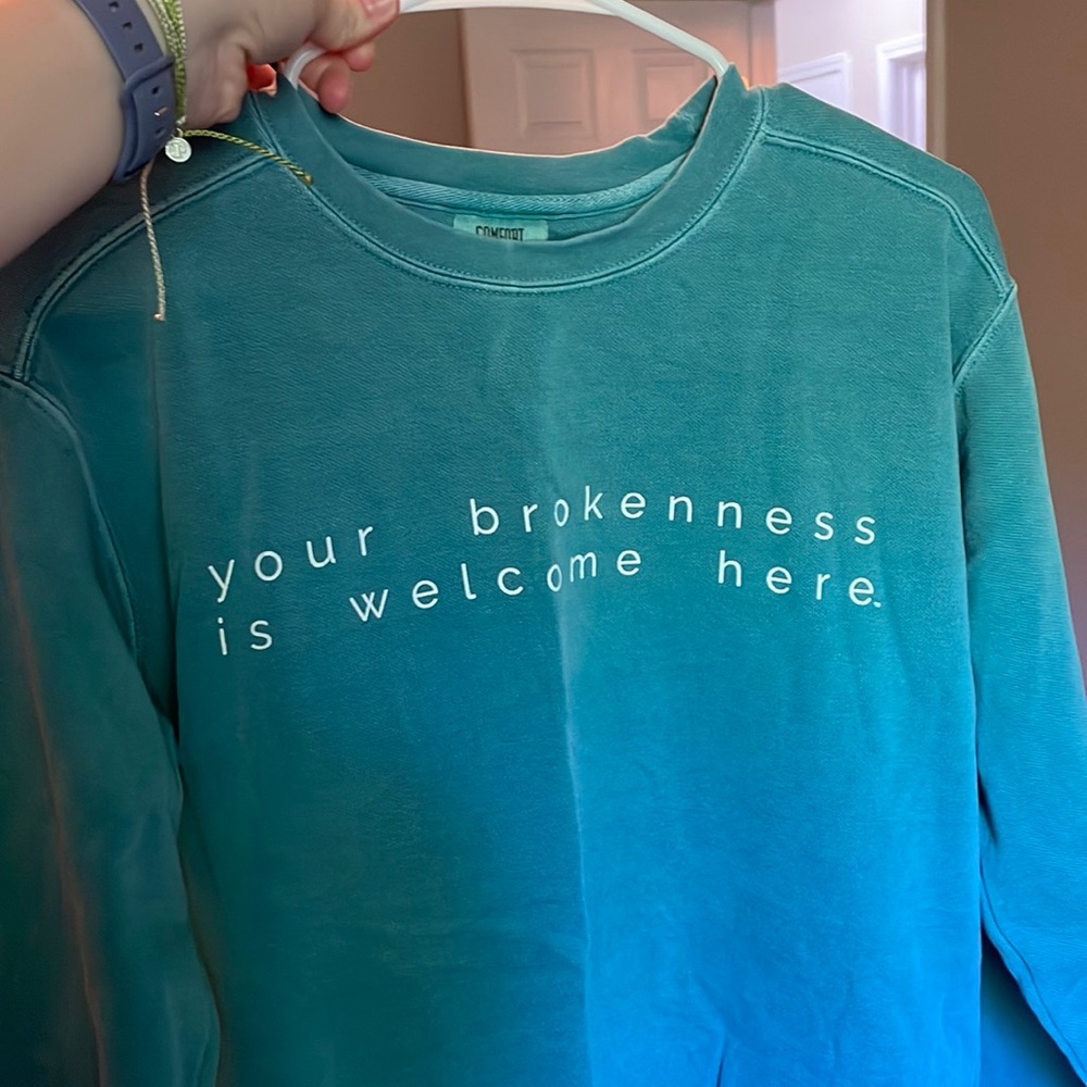 “Your brokenness is welcome here” sweatshirt.